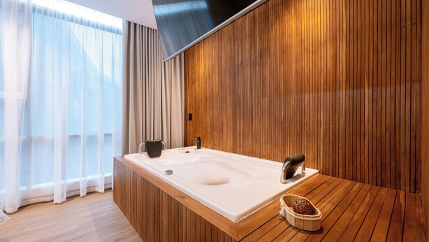 A modern bathroom with a wooden vanity, a large bathtub, and a wooden floor.