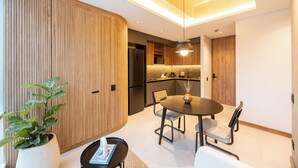 A modern kitchen with wooden cabinetry, a dining area with a round table and chairs, and a potted plant.
