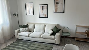 A living room with a sofa, a green armchair, a floor lamp, and a side table. - MADDY'S HOUSE Spacious apartment furnished with care and originality  (Mandello del Lario)