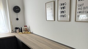 A modern kitchen with a long wooden countertop, a black clock, and three framed signs on the wall. - MADDY'S HOUSE Spacious apartment furnished with care and originality  (Mandello del Lario)