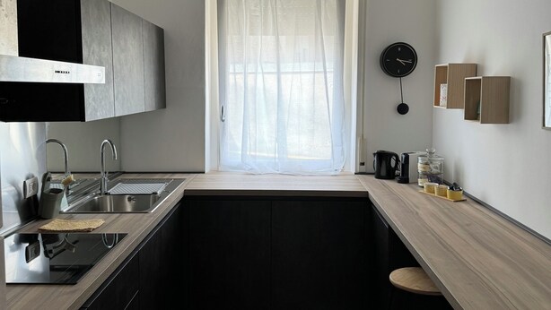 A modern kitchen with a built-in stove, sink, and bar area. - MADDY'S HOUSE Spacious apartment furnished with care and originality  (Mandello del Lario)