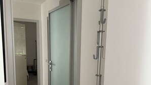 A hallway with a glass door leading to a room, a tiled floor, and a metal pole with hooks. - MADDY'S HOUSE Spacious apartment furnished with care and originality  (Mandello del Lario)