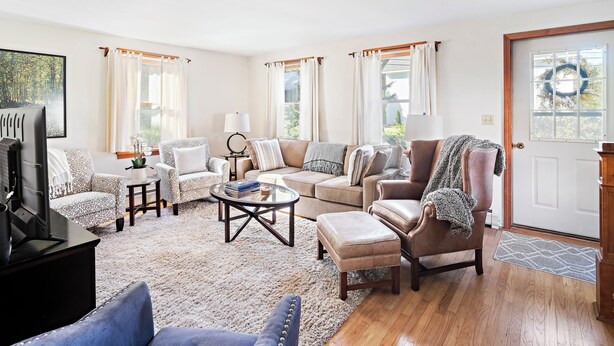 A living room with a sofa, armchairs, a coffee table, and a television.