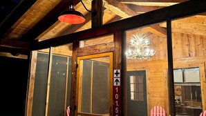 Une cabane en bois avec de grandes fenêtres et une chaise rouge à l’extérieur.