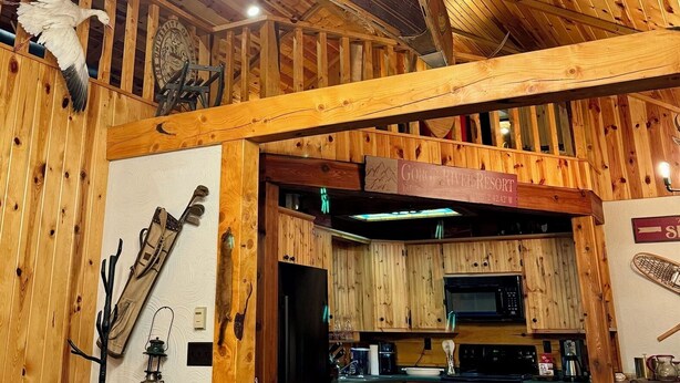 Un intérieur rustique en bois, avec des poutres apparentes, un coin cuisine et un espace repas.