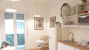 Una cocina compacta con un lavamanos, un pequeño comedor con una mesa y sillas, y un refrigerador.