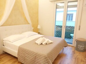 A bedroom with a bed, a nightstand, a lamp, and a view of the outdoors through a sliding door. - Romito 38 (Florence)