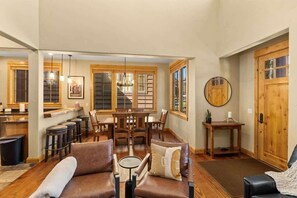 Amplia sala de estar con mesa de comedor, sofás de cuero y una cocina al fondo.