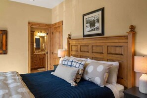 Une chambre à coucher avec une tête de lit en bois, un lit avec une literie bleue et blanche, une table de chevet avec une lampe et un tableau encadré au mur.