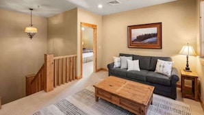 A living room with a sofa, coffee table, and a painting on the wall. - 3-Bed Townhome in Big Sky Town Center (Big Sky)
