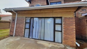 A two-story house with a brick facade, a large sliding glass door, and a concrete driveway. - Value for Money Apartment in Newcastle (Newcastle)