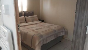 A small bedroom with a bed, a nightstand, and a wall-mounted light. - Value for Money Apartment in Newcastle (Newcastle)