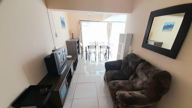 A living room with a sofa, TV, and a dining area in the background. - Value for Money Apartment in Newcastle (Newcastle)