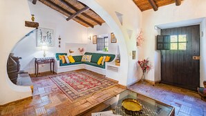A cozy interior with a wooden ceiling, a green sofa with yellow cushions, a patterned rug, and a wooden floor.