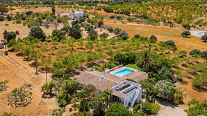 A house with a swimming pool, surrounded by trees and a hilly landscape.
