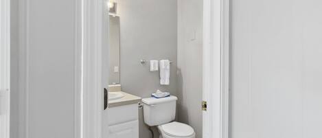 Een kleine badkamer met toilet, wastafel en spiegel.