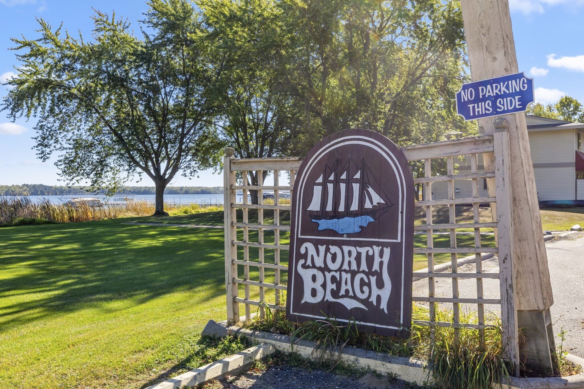 A wooden gate with a sign that reads "North Beach" and a "No Parking This Side" sign.