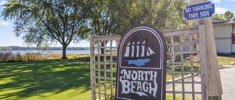A wooden gate with a sign that reads "North Beach" and a "No Parking This Side" sign.