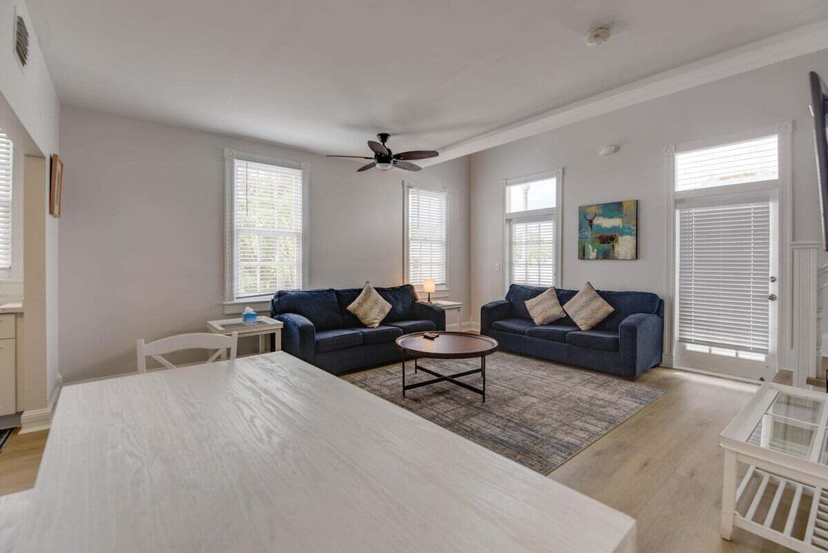 A spacious living room with two dark blue sofas, a round coffee table, and a white dining table.