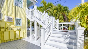 A yellow building with white railings and a wooden deck. - Leo's Lodge | Newly Updated! (Key West)