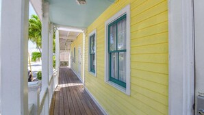 A narrow wooden corridor with white railings and a yellow exterior wall. - Carey's Corner | Updated Studio with Heated Pool (Key West)