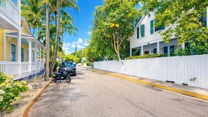 En bostadsgata med hus, ett vitt staket och en parkerad motorcykel.