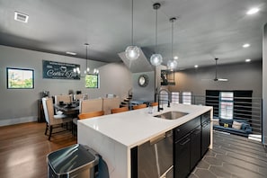 A modern kitchen with a large island, dining area, and a coffee bar sign.