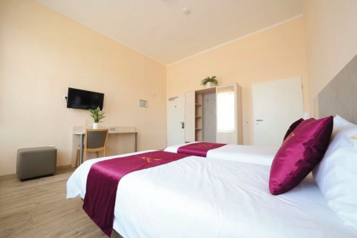 A hotel room with two beds, a desk, a television, and a wardrobe.