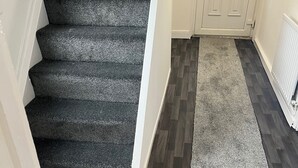 Eine Treppe mit dunklem Teppich, die zu einer weißen Tür führt.