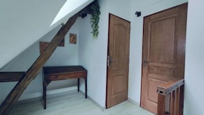 A room with a wooden staircase, a bench, and two wooden doors.