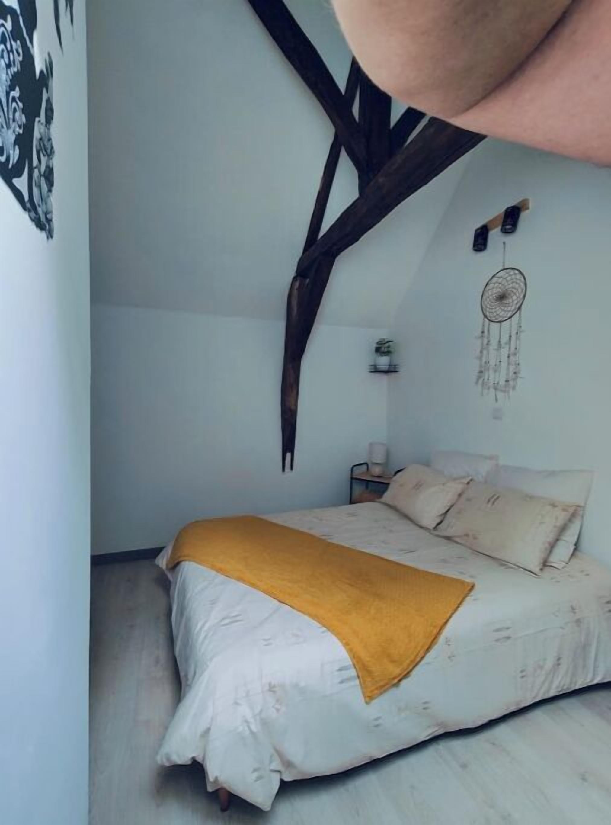 Una camera da letto con un letto, un comodino, un dreamcatcher e travi in legno a vista.