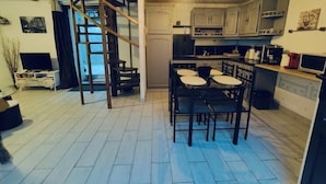 A compact kitchen with a dining area, a staircase, and a TV in the living area.