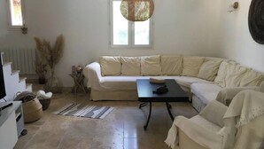 En stue med en beige modulsofa, et lille sort bord og en hængende lampe.