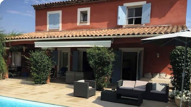 Et toetagers hus med swimmingpool, udendørs siddepladser og en overdækket terrasse.