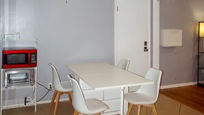 A small, modern room with a white table and four chairs, a microwave, and a small oven. - Peaceful Home In The Heart of TLH (Tallahassee)