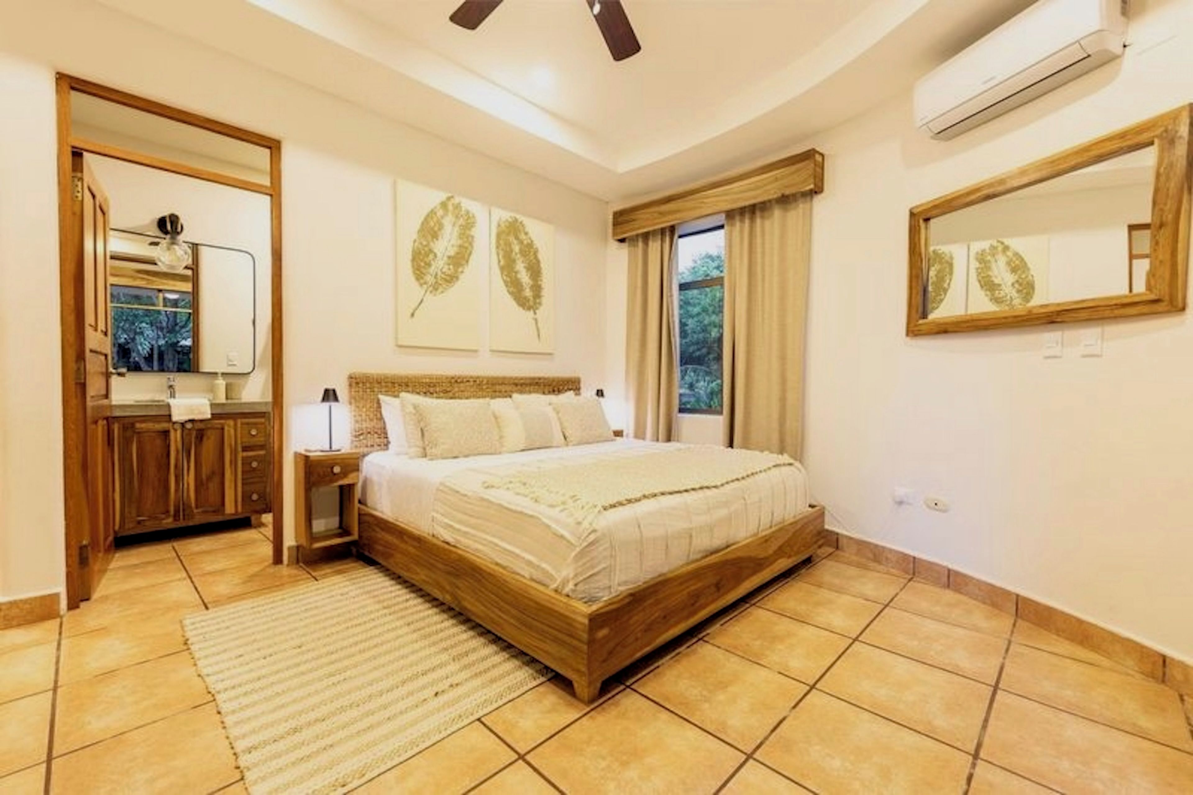 A bedroom with a wooden bed, a nightstand, a mirror, and a window with curtains.
