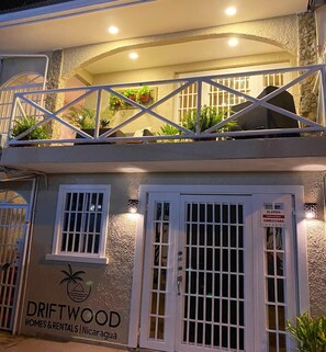 Un bâtiment à deux étages doté d’un balcon, d’une enseigne indiquant « DRIFTWOOD HOMES & RENTALS Nicaragua » et d’un système d’alarme de sécurité.