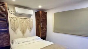 Een slaapkamer met een bed, airconditioning, een garderobe en een groot raam.