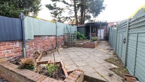 A backyard with a brick planter, a wooden bench, and a small garden area.