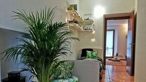Ein gemütlicher Wohnbereich mit einem grünen Sofa, einem Topf mit Pflanze und einer Treppe, die in einen anderen Raum führt.