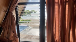 A room with a large sliding glass door leading to a pool area.