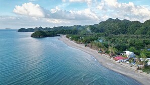 A coastal landscape with a beach, a small island, and a mountain range in the background. - Suite Room 1 (Sipalay City)