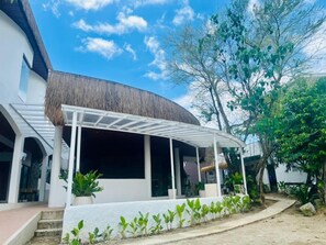 A modern house with a curved roof, a covered porch, and a garden with young plants. - Suite Room 2 Beach Front (Sipalay City)