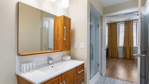 A modern bathroom with a large mirror, wooden vanity, and a glass shower enclosure.