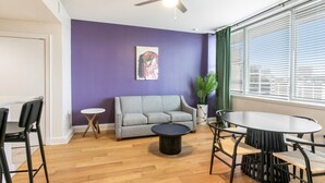 A room with a grey sofa, a round table, and a ceiling fan.