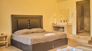 A hotel room with a bed, a bathroom with a sink and mirror, and a shower area.