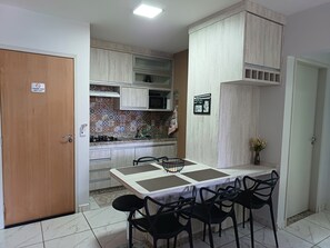 Enjoy meals in this cozy kitchen with a dining table for four, featuring a stainless steel range hood and a tiled backsplash.