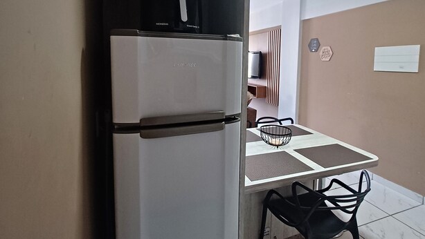 Une cuisine compacte équipée d’un réfrigérateur intégré, d’un four à micro-ondes et d’un petit coin repas avec une table et des chaises.