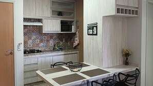 Une cuisine compacte avec un coin repas, dotée d’un crédence carrelée, d’un four à micro-ondes et d’une cuisinière à gaz.