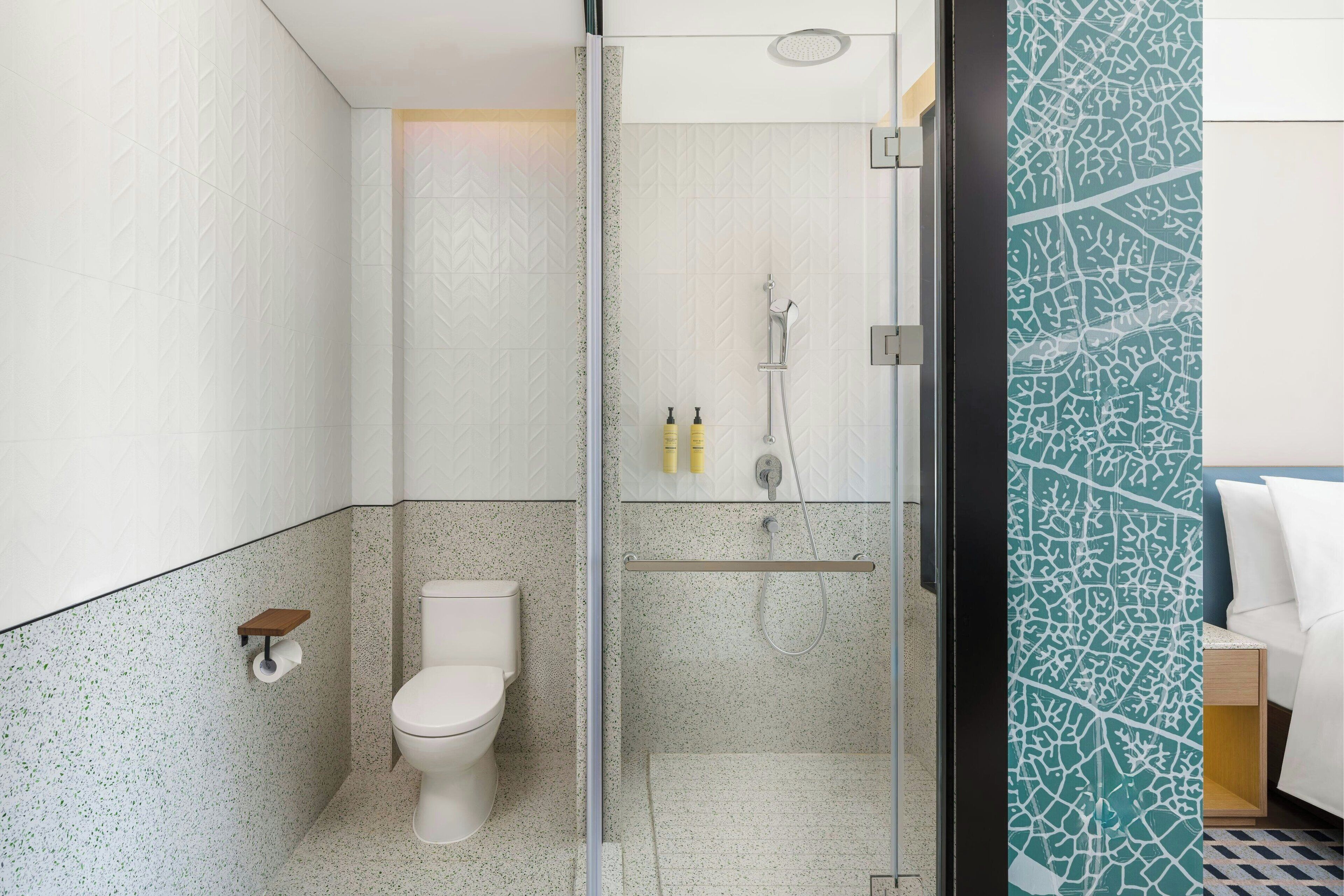 A modern bathroom with a toilet, shower, and a glass partition.